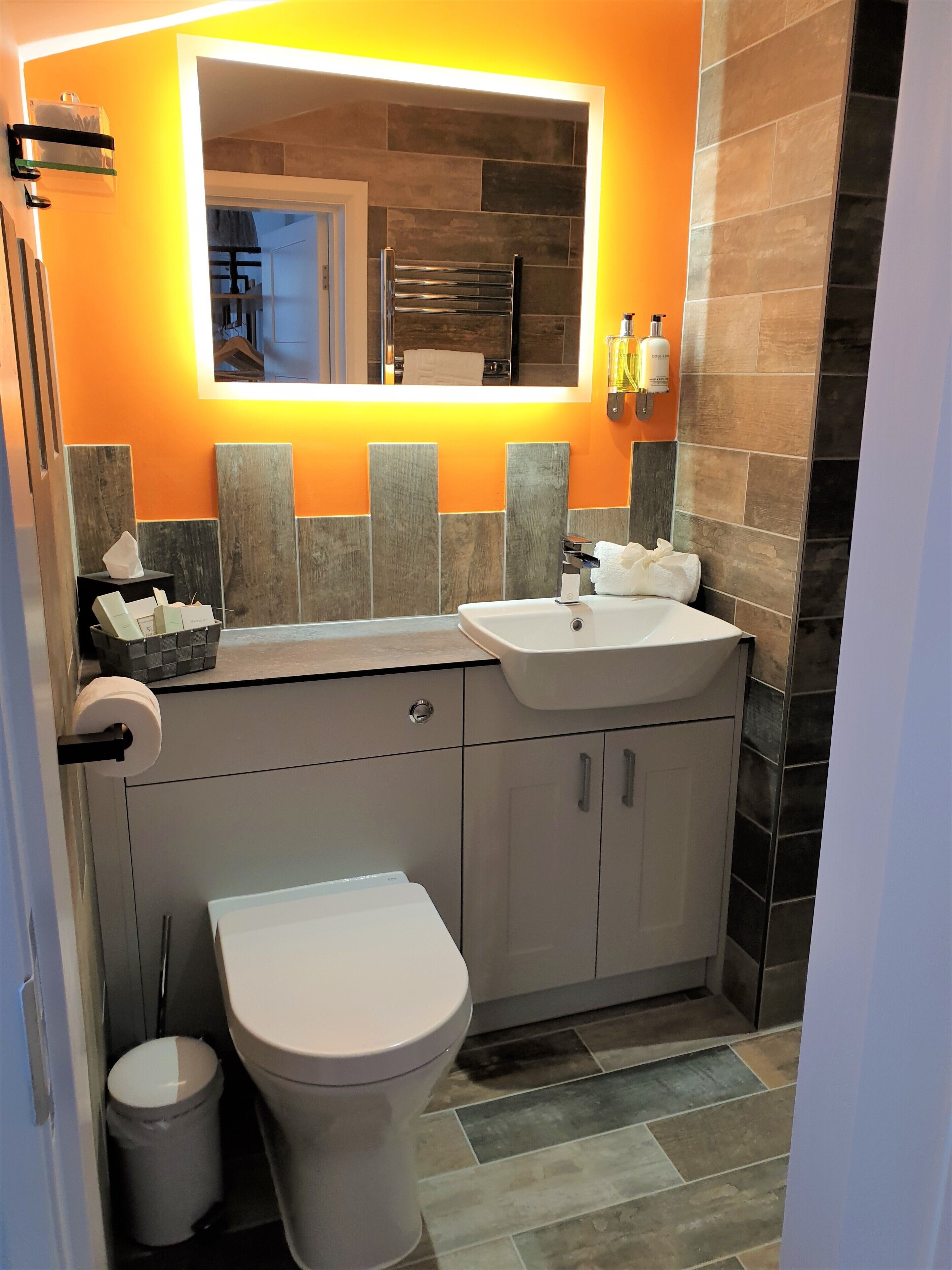 Een moderne badkamer met een wit wastafel, een toilet en een spiegel boven het wastafel.