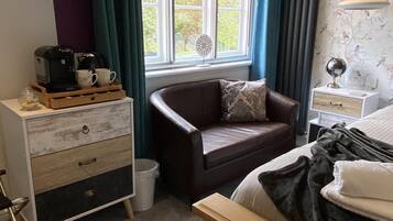 Un dormitorio con una cama, una mesita de noche, un aparador, una ventana con cortinas y una mesilla con lámpara.