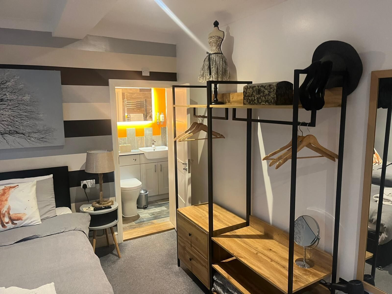 Un dormitorio con cama, mesita de noche, lámpara y armario con espejo.