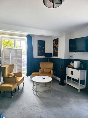 A room with a sofa, a chair, a round table, a cabinet, and artwork on the wall. - Copperbeech Bed and Breakfast (Saxmundham)