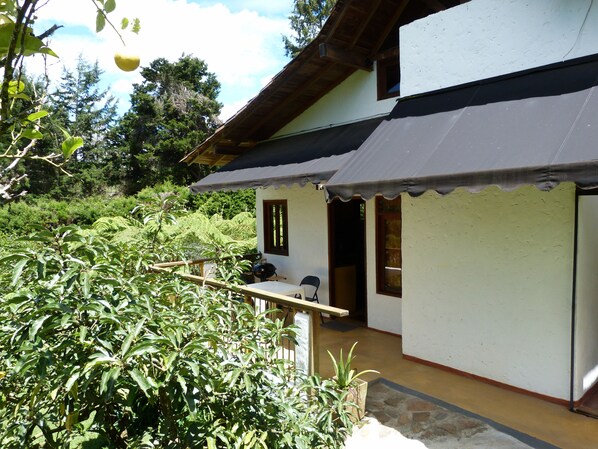 Une maison avec un porche, un petit jardin et une terrasse en bois.
