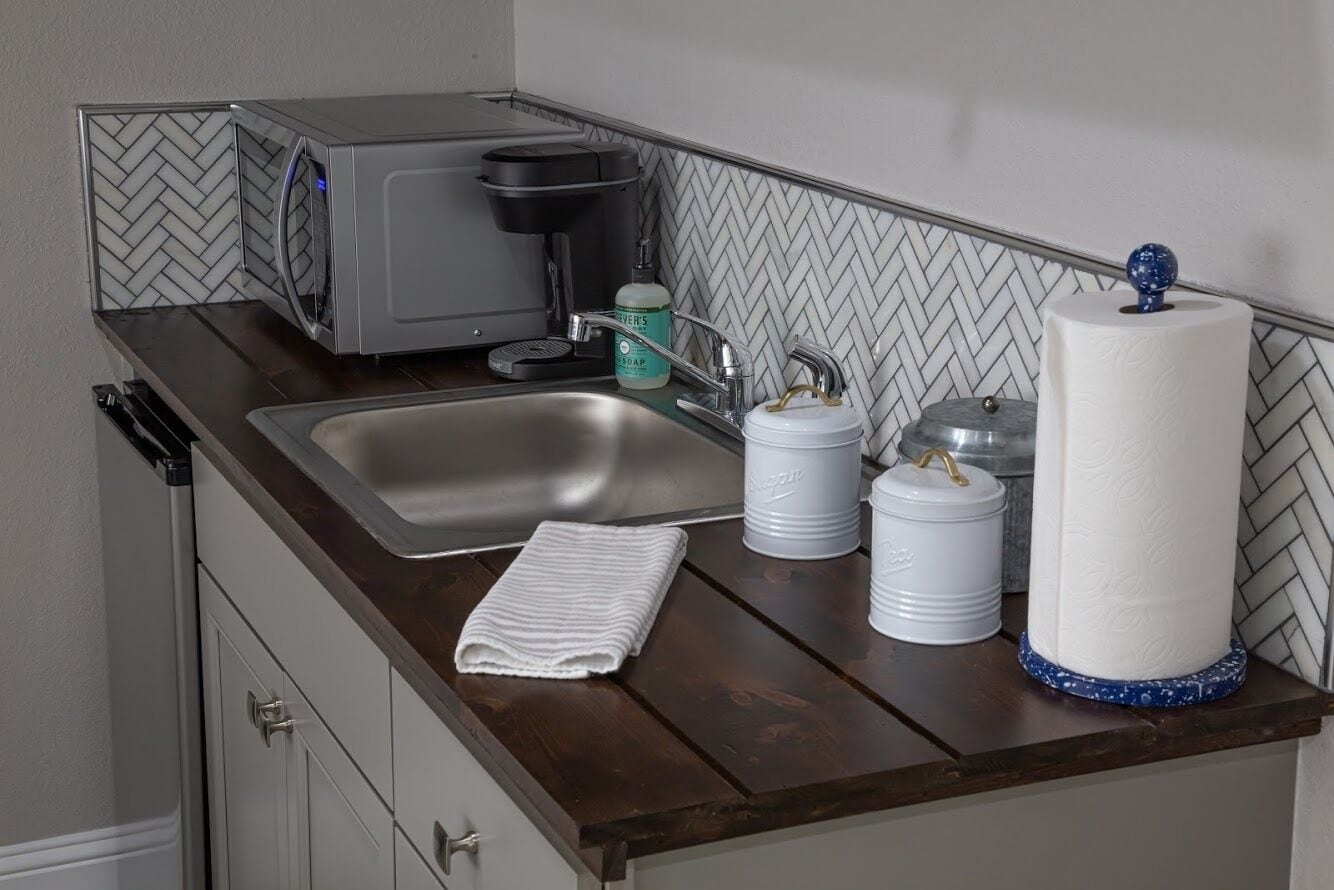 Cozinha equipada com micro-ondas, máquina de café, pia e artigos de higiene pessoal.