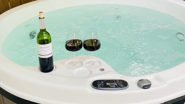 Een jacuzzi met een fles wijn en twee glaasjes.