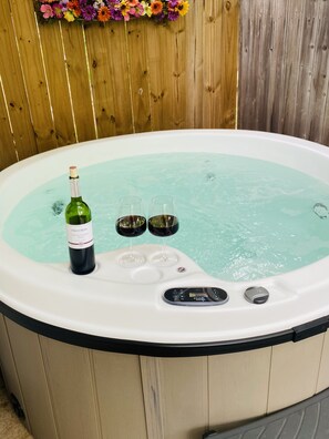 A hot tub with a bottle of wine and two glasses. - Four blocks of Main Street!!! (Fredericksburg)