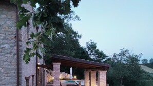 A stone patio with a pool table, outdoor seating, and a pergola. - Rustic stone house with a modern touch (Civitella Casanova)