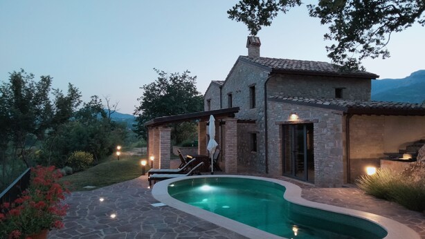 A stone house with a swimming pool, outdoor seating, and a view of the mountains. - Rustic stone house with a modern touch (Civitella Casanova)