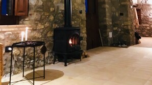 A stone interior with a fireplace, wooden beams, and a stone wall. - Rustic stone house with a modern touch (Civitella Casanova)
