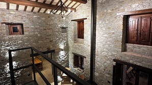 A rustic interior with exposed stone walls, wooden beams, and a wooden staircase. - Rustic stone house with a modern touch (Civitella Casanova)