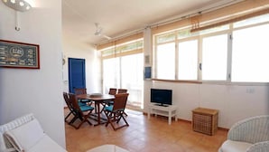 Un'ampia zona giorno con tavolo da pranzo, sedie, televisore e mobili in vimini.