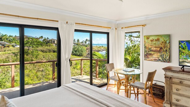 A bedroom with a large sliding glass door leading to a balcony with a view of a coastal landscape. - Poipu Beach Kauai Honeymoon : View Sea Turtles from Your Oceanfront Deck-AC (Koloa)