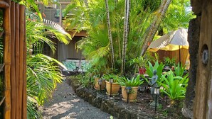 A pathway lined with potted plants and a thatched roof structure. - Poipu Beach Kauai Honeymoon : View Sea Turtles from Your Oceanfront Deck-AC (Koloa)