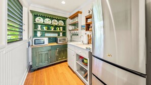A kitchen with a refrigerator, microwave, and wooden cabinets. - Poipu Beach Kauai Honeymoon : View Sea Turtles from Your Oceanfront Deck-AC (Koloa)
