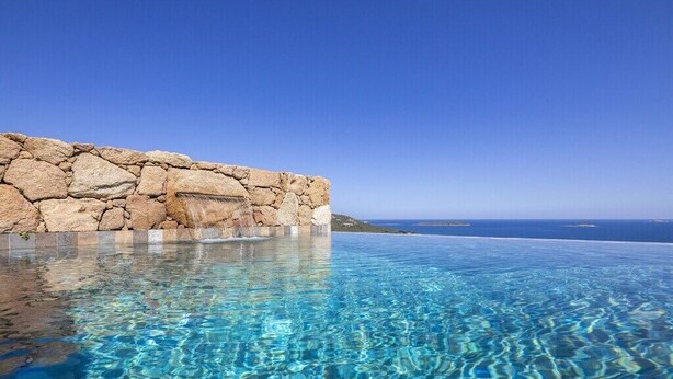 A clear infinity pool with a stone wall and a view of the ocean. - Villa 17 - Panoramic view of Palombaggia (Porto-Vecchio)