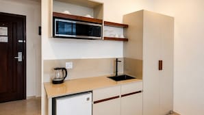 A compact kitchen with a microwave, sink, and a small refrigerator. - Spanhoek Boutique Hotel (Paramaribo)