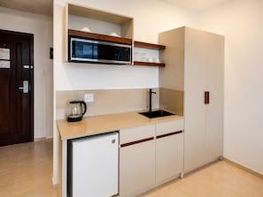 A compact kitchen with a microwave, sink, and a small refrigerator. - Spanhoek Boutique Hotel (Paramaribo)