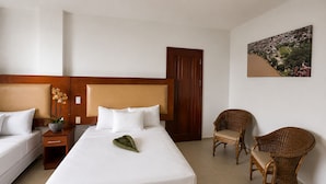 A hotel room with a large bed, two bedside tables, a chair, and a wall-mounted painting. - Spanhoek Boutique Hotel (Paramaribo)