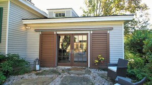 A house with a patio area featuring a stone pathway, a wicker chair, and a lantern. - Historic Cottage with modern amenities (louisville)