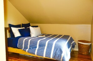 A bed with a striped blue and white bedspread, a wooden headboard, and a small wicker basket beside the bed. - Lakeside Adventurer's Cabin (Durango)