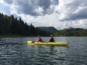 Two people in a yellow kayak on a lake with a forested mountain in the background. - Lakeside Adventurer's Cabin (Durango)