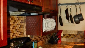 A kitchen with wooden cabinets, a stove, a microwave, and a hanging pot rack. - Lakeside Adventurer's Cabin (Durango)