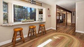 Una cocina con un ventanal grande, taburetes de madera y una alfombra.