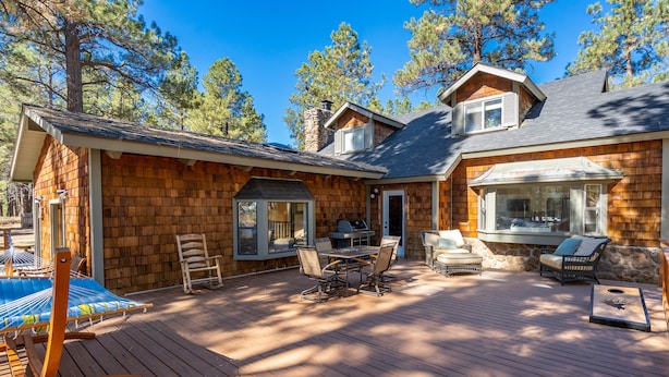 Una cabaña de madera con terraza, mobiliario exterior y zona de barbacoa.