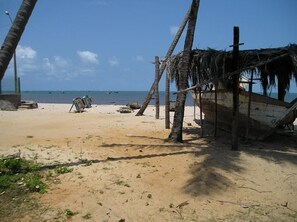 Ein Strand mit einer strohgedeckten Hütte, Palmen und einem sandigen Ufer.