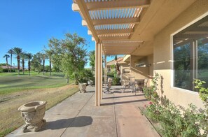 Relax in the serene surroundings of this outdoor patio, complete with a pergola, seating area, and lush greenery.