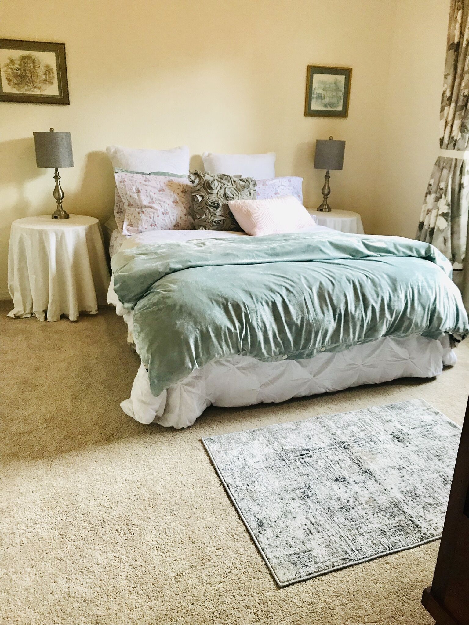 A bedroom with a bed, two bedside tables, a rug, and two wall-mounted lamps.