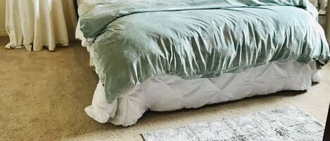 A bedroom with a bed, two bedside tables, a rug, and two wall-mounted lamps.