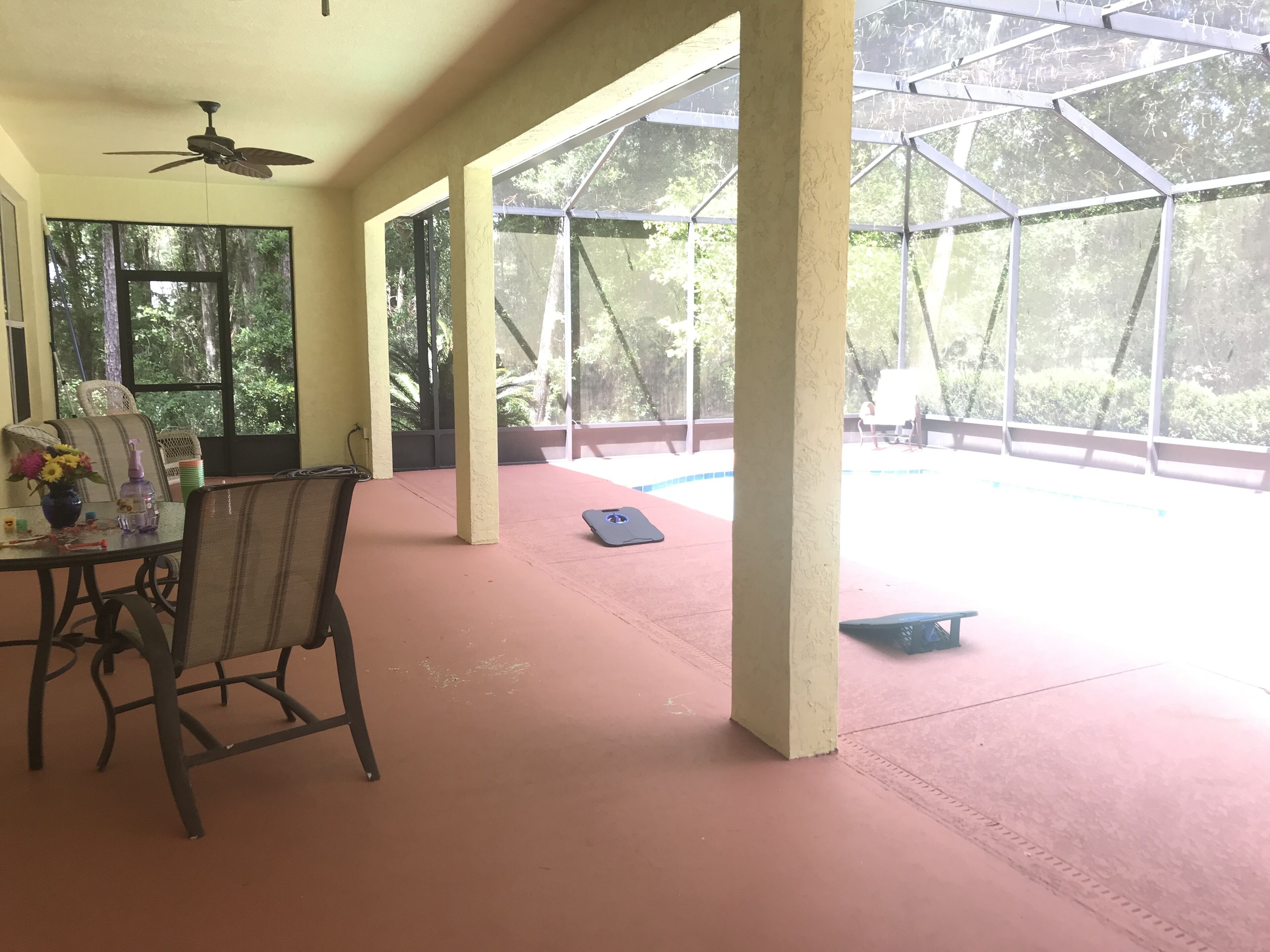 Un patio techado con una mesa, sillas y un ventilador de techo.