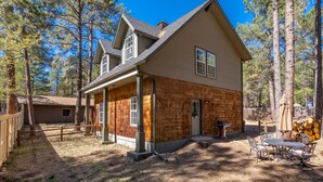 A two-story house with a covered porch, a fireplace, and a dining area with outdoor furniture. - Magdalena Cottage on 1/2 acre (Flagstaff)