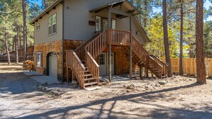 A two-story house with a wooden deck and a staircase leading to the second floor. - Magdalena Cottage on 1/2 acre (Flagstaff)