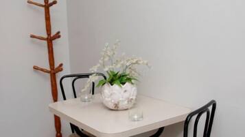A dining table with chairs, a potted plant, and a wall-mounted light fixture.