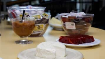 A table with a plate of white cheese, a glass of iced coffee, and two bowls of food.