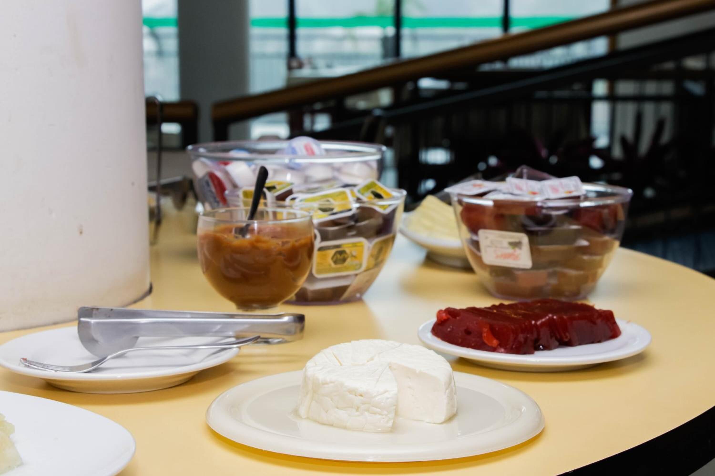 Ein Tisch mit verschiedenen Speisen, darunter ein weißer Käse, ein rotes Jelliedessert und mehrere Gewürzbehälter.