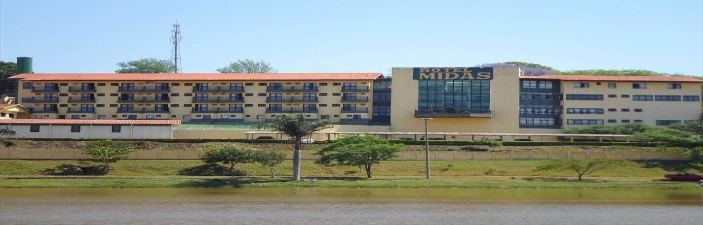 A hotel with a prominent 'HOTEL MIDAS' sign, multiple floors, and a flat roof.