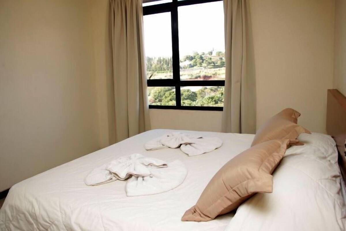 Una cama bien hecha con vistas a un paisaje a través de una ventana.