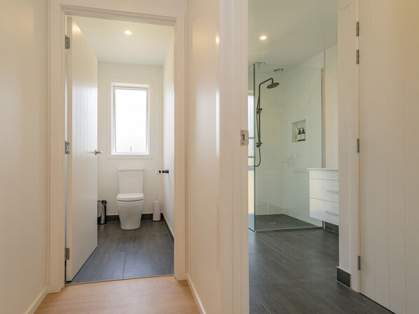 Een moderne badkamer met toilet, douche en witte kastjes.
