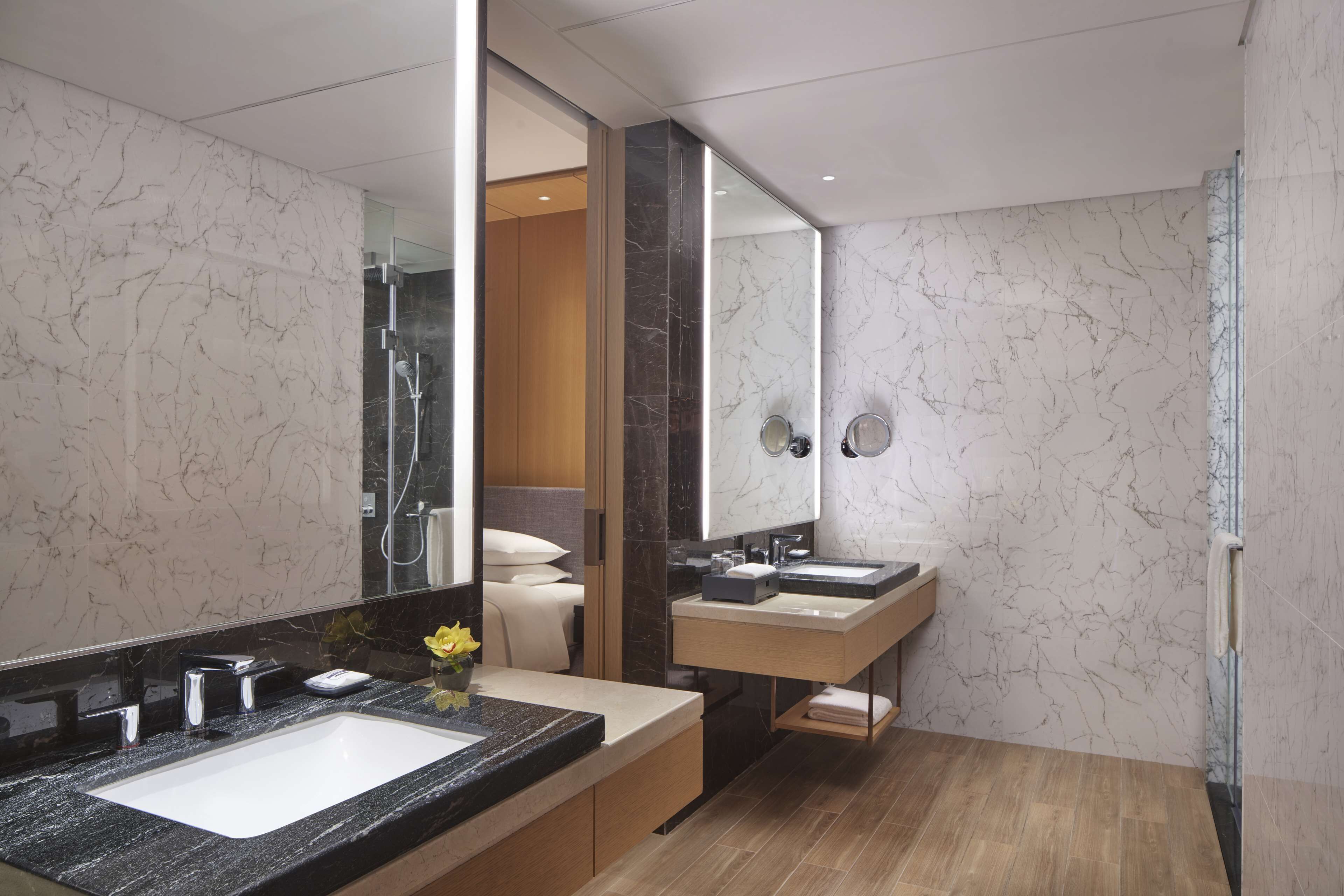Un baño moderno con un espejo grande, dos lavamanos y una zona de ducha.
