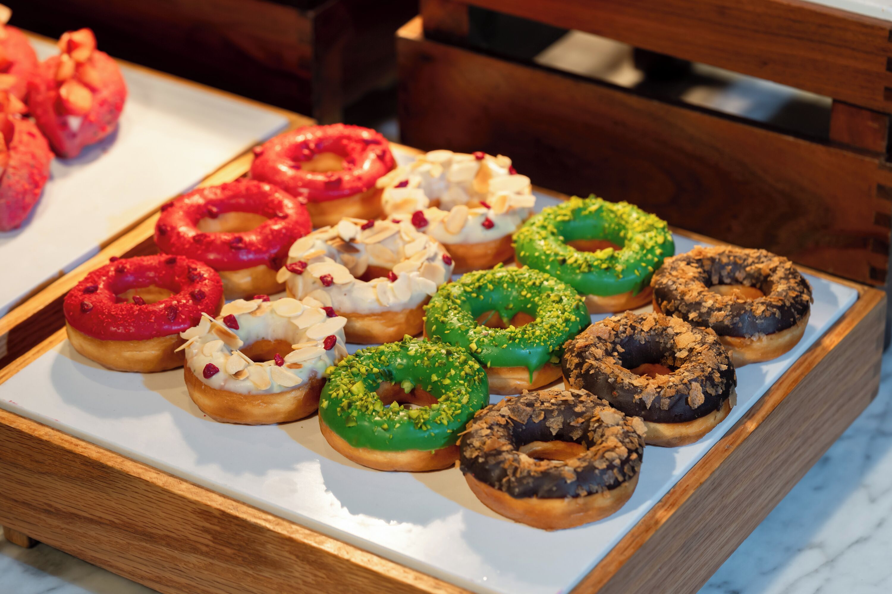 A tray of assorted donuts with various toppings and colors.