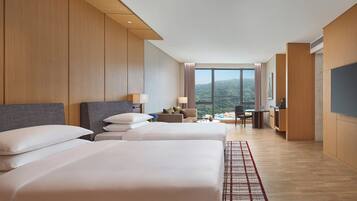A hotel room with two beds, a desk, a chair, and a TV.