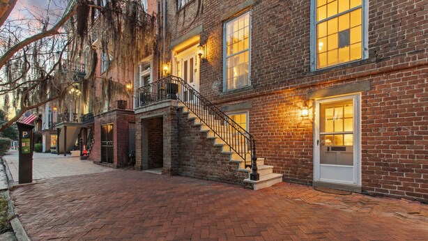 A brick building with a staircase leading to a second floor, a mailbox, and a door with a window.