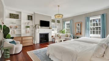 Un dormitorio amplio con una cama grande, un sofá y una chimenea. Hay estantes con objetos decorativos y un televisor.