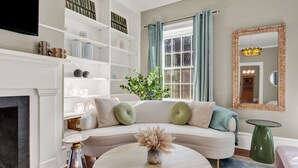 A living room with a white sofa, a round coffee table, a fireplace, and a bookshelf.