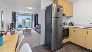 A modern kitchen with a stainless steel refrigerator, wooden cabinets, and a built-in oven. - Wonderful Apt in CBD Neighbourhood I Zodiak Stays (Auckland)