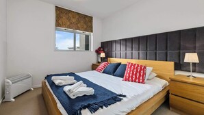 A bedroom with a bed, bedside tables, a radiator, a window with a view, and a headboard. - Wonderful Apt in CBD Neighbourhood I Zodiak Stays (Auckland)