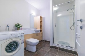 Ein modernes Badezimmer mit Waschmaschine, Toilette, Waschbecken und Duschkabine.