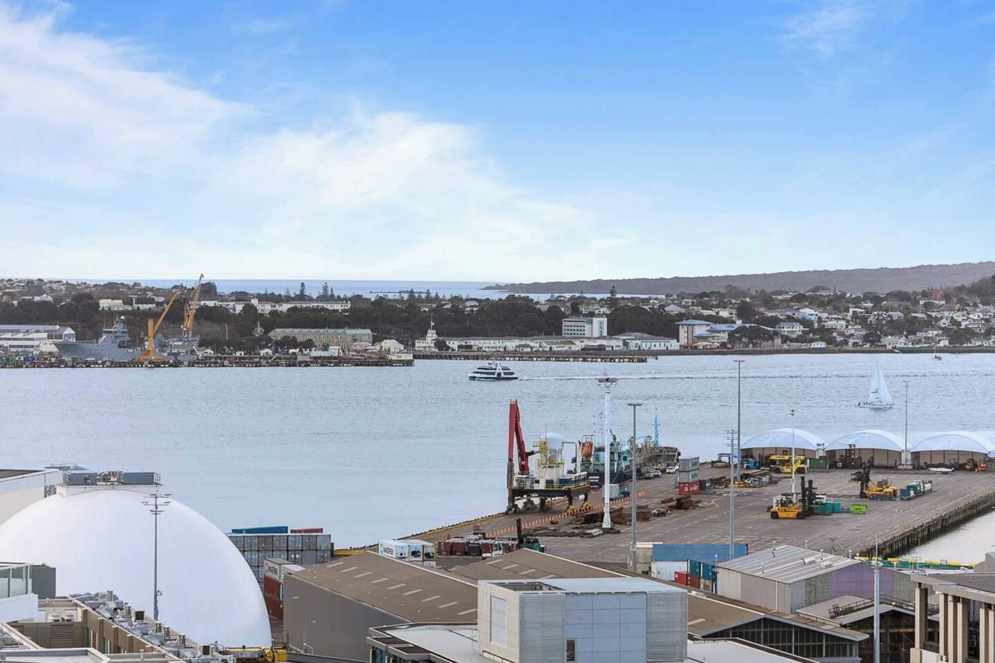 Een kustgebied met industrie, een groot wateroppervlak, kranen en zeecontainers.