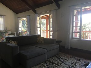A living room with a sofa, patterned curtains, and a view of a wooden deck.